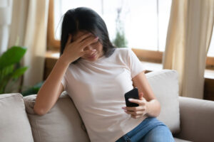 Asian woman holds smartphone read unpleasant message feels desperate